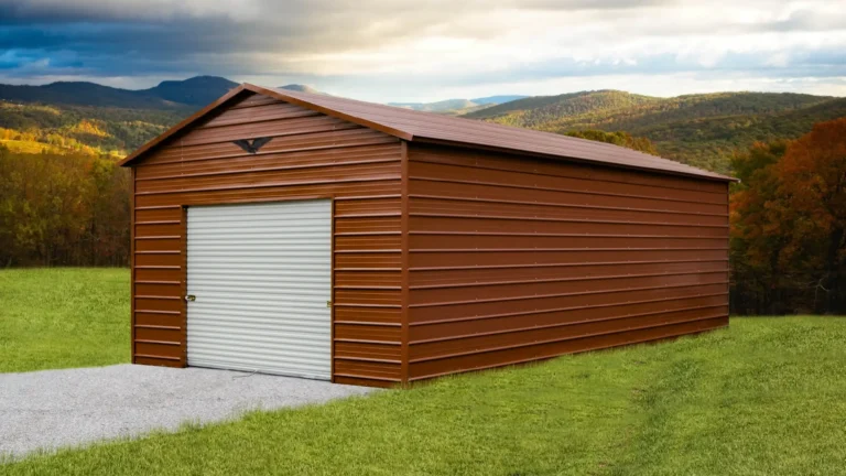 18x35x10 boxed eave roof metal garage with brown siding and a roll-up door on a gravel pad in a scenic mountain setting. This extra-long metal garage offers secure storage for vehicles and equipment, and Eagle Carports provides metal garages for sale to protect your property.